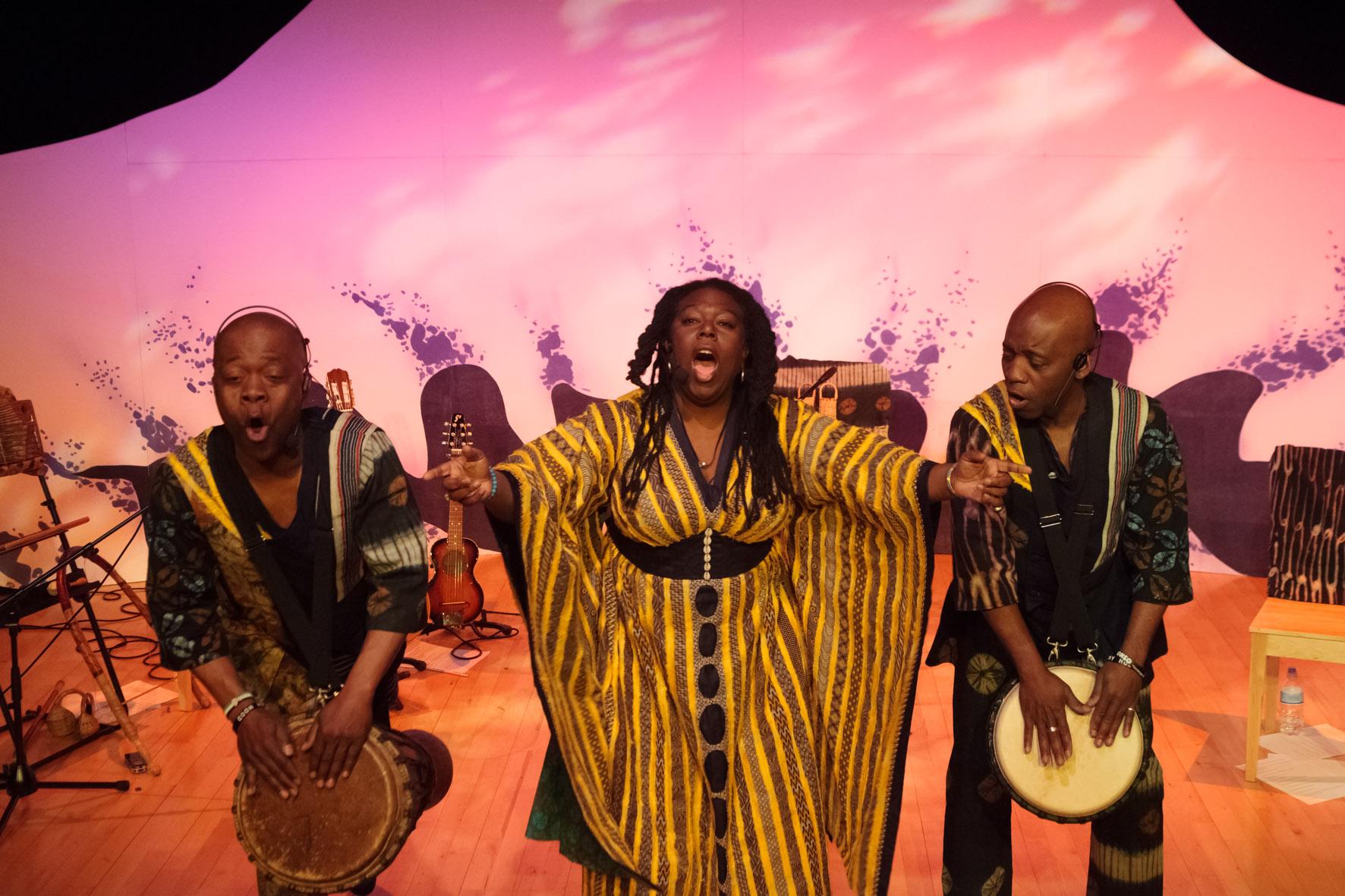 an ensemble shot of (L-R) Raymond Sereba, Jan Blake & Koumae Sereba performing on stage