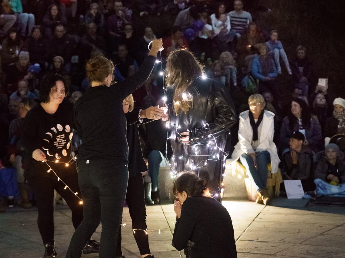 a group of performers at night at the stardisc in wirksworth winding fairy lights around each other