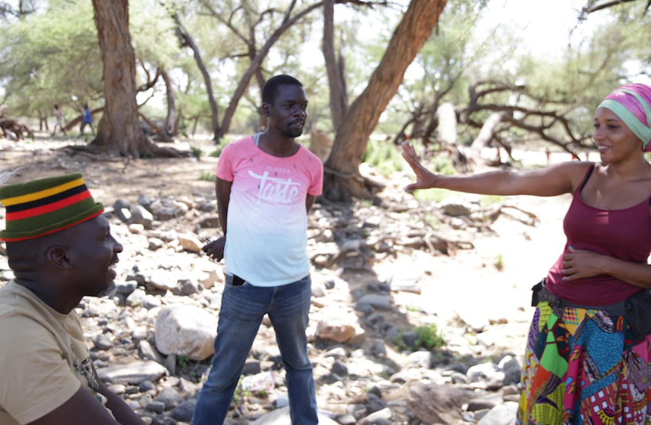 Storytellers John Namai (left) and Mara Menzies (right) interview Abdi Achegei Adan, the Director of Elemi Development Organization, an organization that works with marginalized communities in northern Kenya, during the Lokiriama Peace Accord Commemoration in Lokiriama village, Turkana County, Kenya