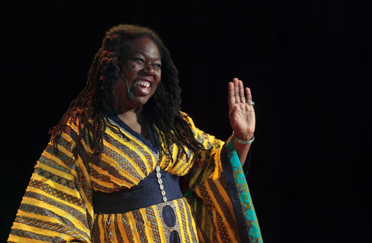 Jan Blake holding up her hand and smiling in performance mode